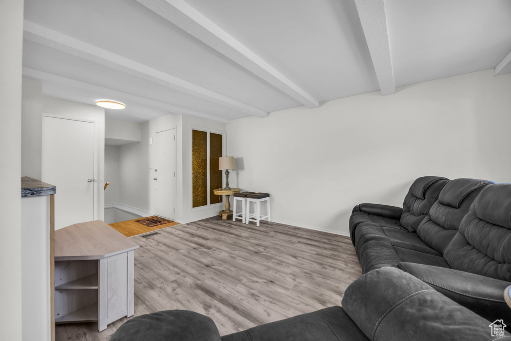 Living area with beam ceiling and light wood-style flooring