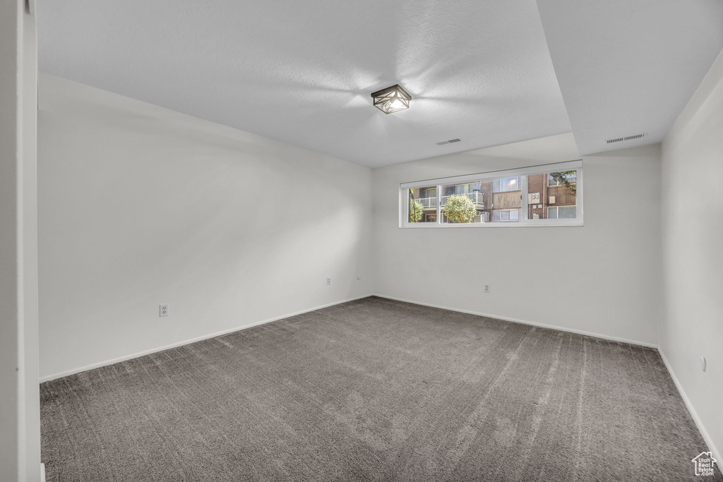 Carpeted spare room featuring baseboards and visible vents