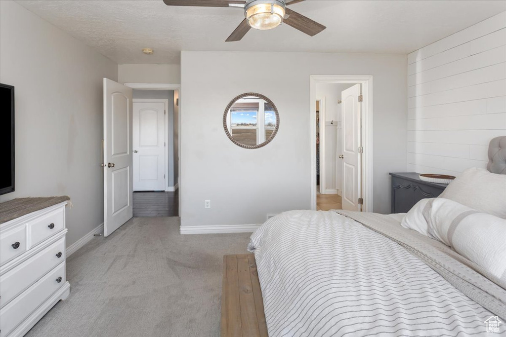 Bedroom with connected bathroom, baseboards, a ceiling fan, and light colored carpet