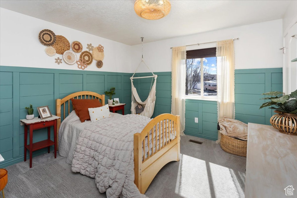 Bedroom with a wainscoted wall, a textured ceiling, and carpet flooring