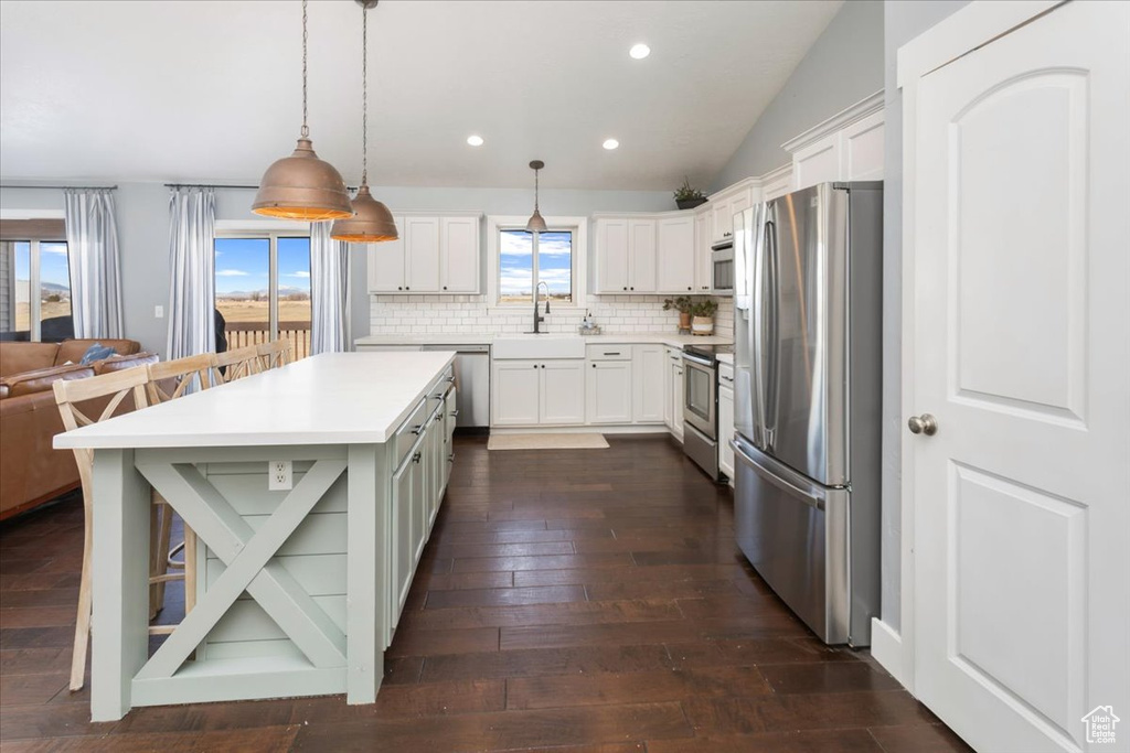 Kitchen featuring a breakfast bar, light countertops, decorative backsplash, appliances with stainless steel finishes, and a sink