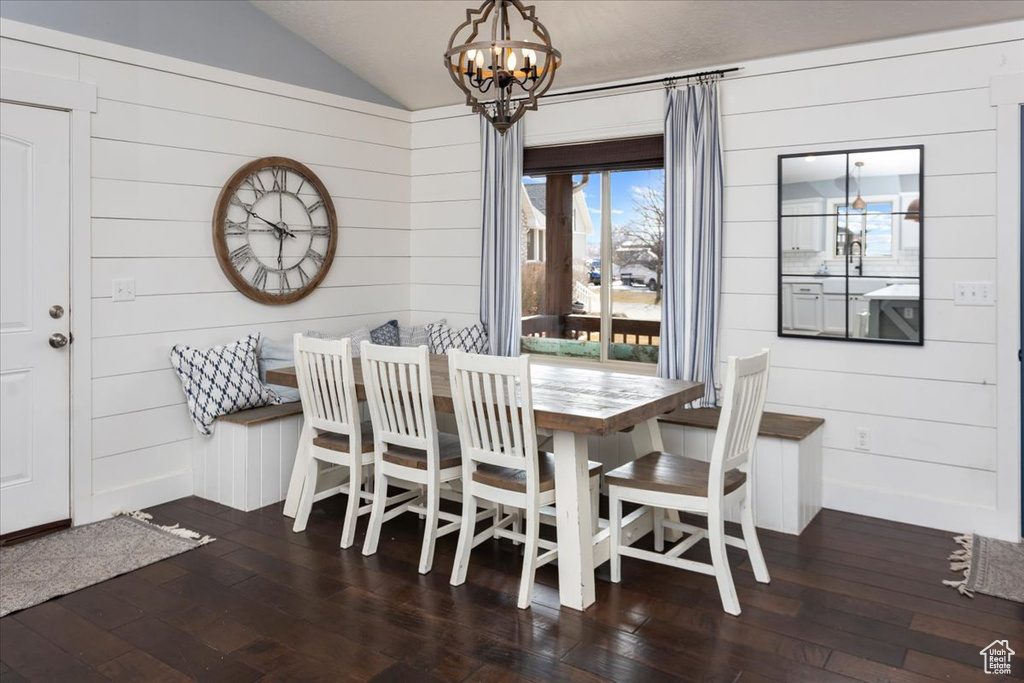 Dining area featuring lofted ceiling, dark wood-type flooring, and an inviting chandelier