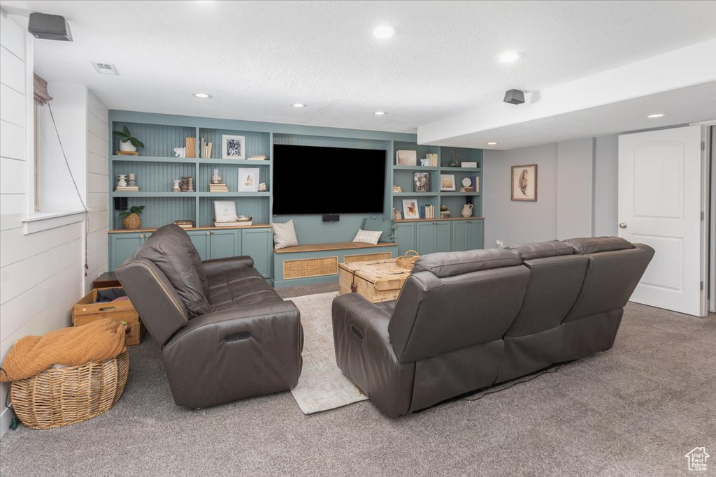 Carpeted living room with built in shelves, recessed lighting, visible vents, and a textured ceiling