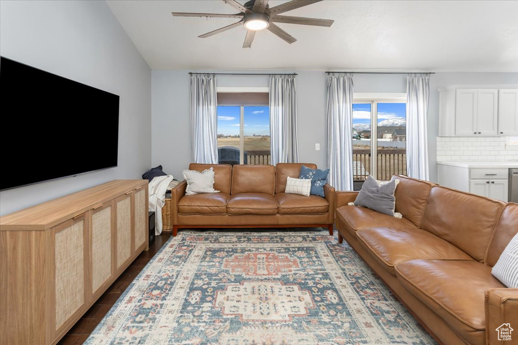 Living room featuring ceiling fan, vaulted ceiling, and dark wood-style flooring