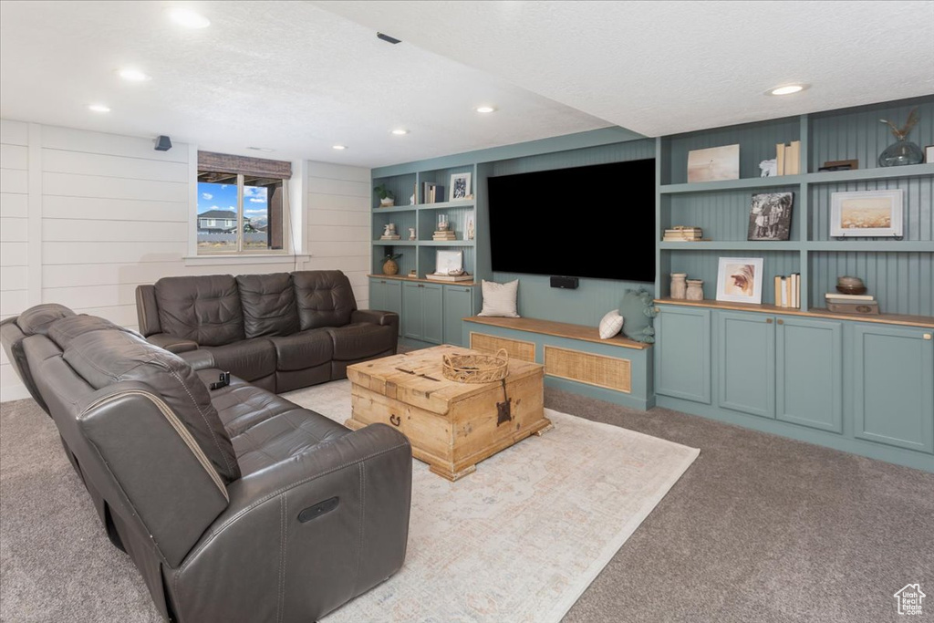Living room featuring carpet floors, built in shelves, a textured ceiling, and recessed lighting
