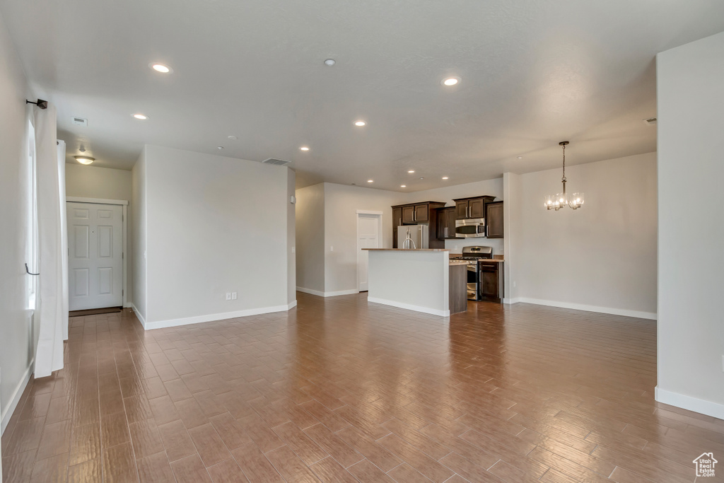 Unfurnished living room with a chandelier, wood finished floors, visible vents, and recessed lighting