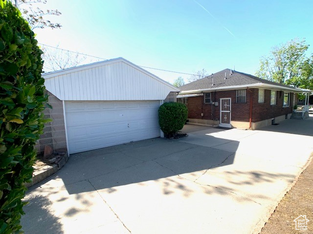 Single story home with a detached garage, an outbuilding, and brick siding