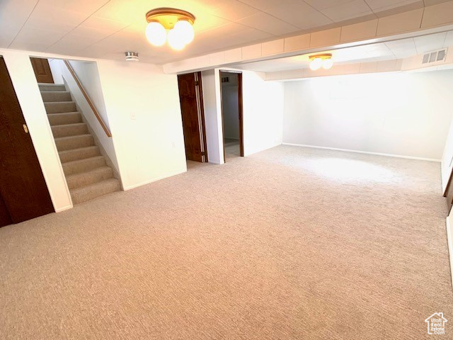Finished basement featuring baseboards, carpet, stairs, and visible vents
