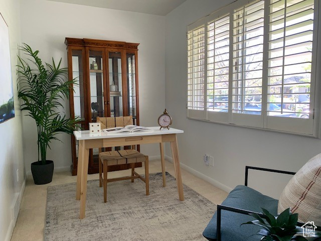 Carpeted home office featuring baseboards