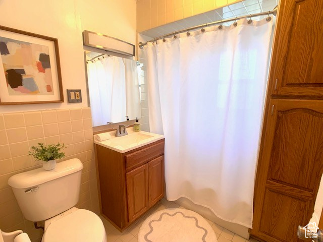 Bathroom with toilet, tile walls, tile patterned flooring, and vanity