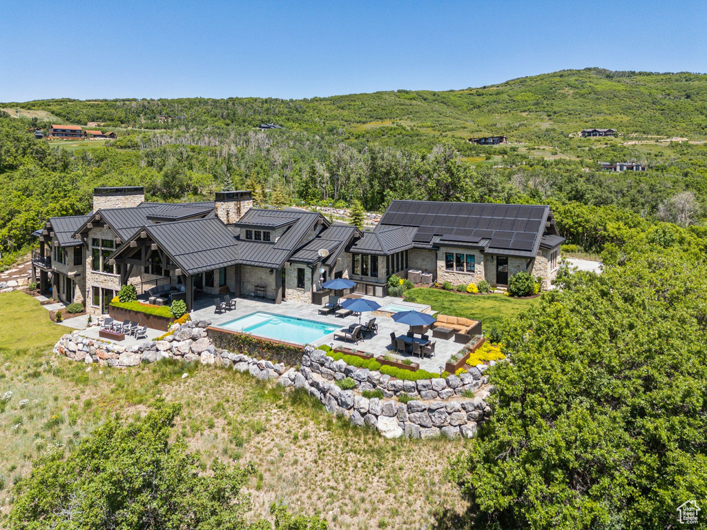 Back of property featuring stone siding, a standing seam roof, outdoor dining space, a chimney, and a patio area