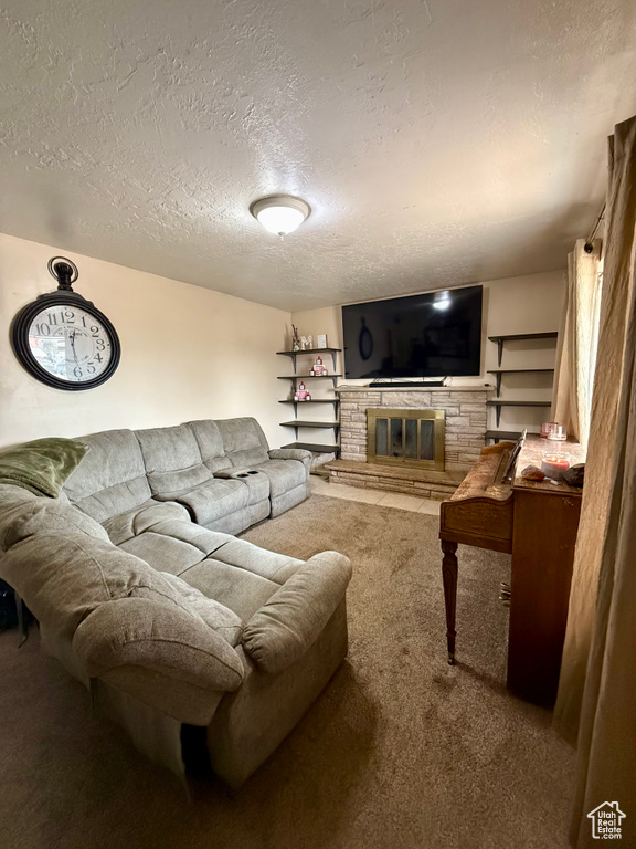 Living room featuring carpet floors, a textured ceiling, and a glass covered fireplace