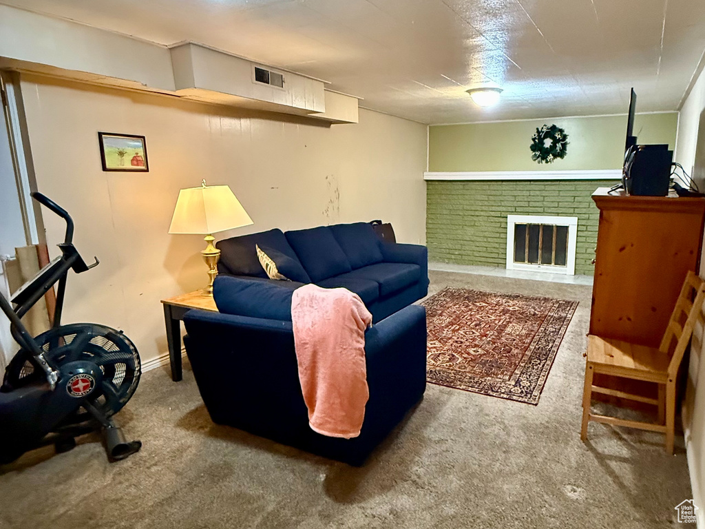 Carpeted living room with a brick fireplace, visible vents, and baseboards