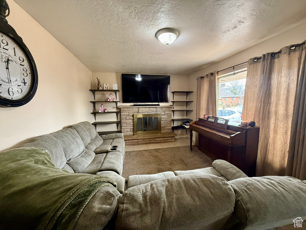 Carpeted living room featuring a textured ceiling and a stone fireplace