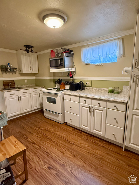 Kitchen featuring white electric range, stainless steel microwave, wood finished floors, and white cabinets