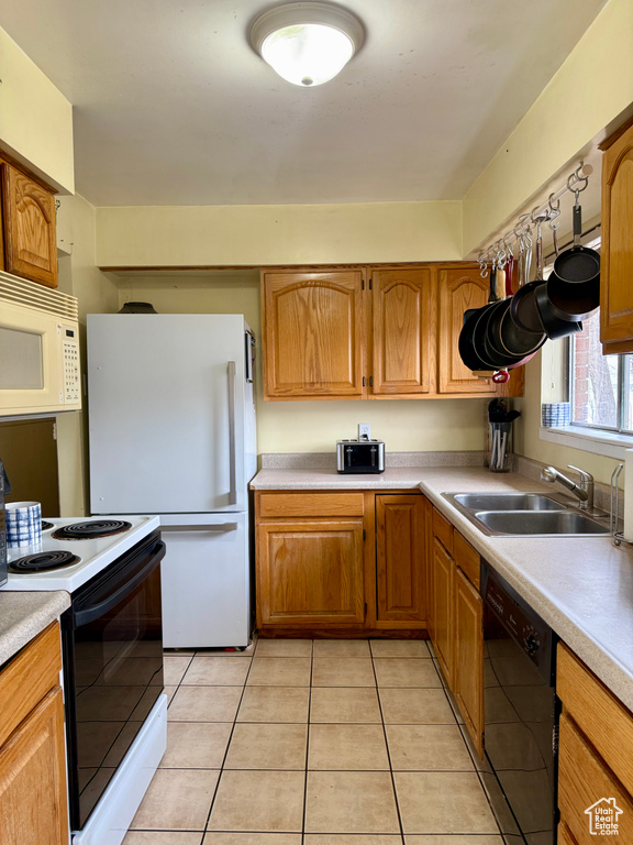 Kitchen featuring white appliances, light countertops, a sink, and light tile patterned flooring
