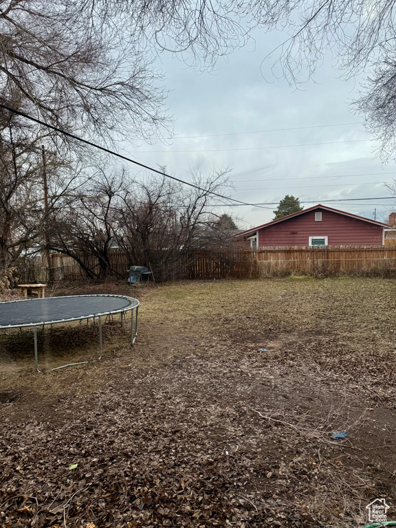 View of yard featuring a trampoline and fence