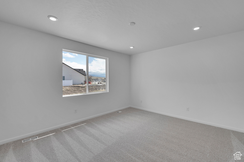 Carpeted spare room with visible vents, baseboards, and recessed lighting