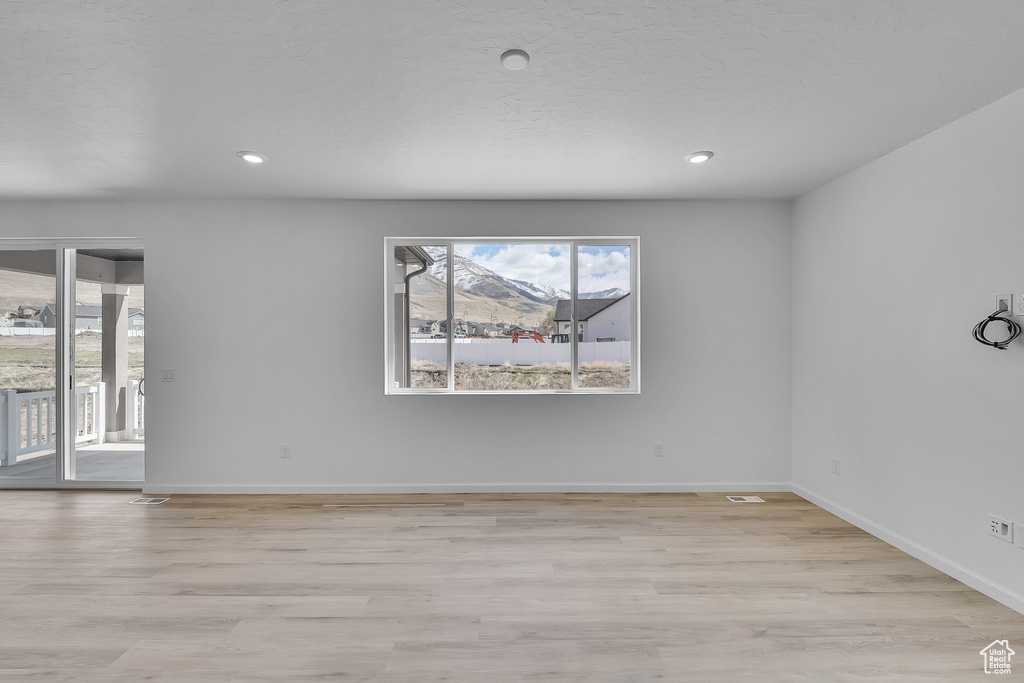 Spare room with baseboards, light wood-type flooring, and recessed lighting