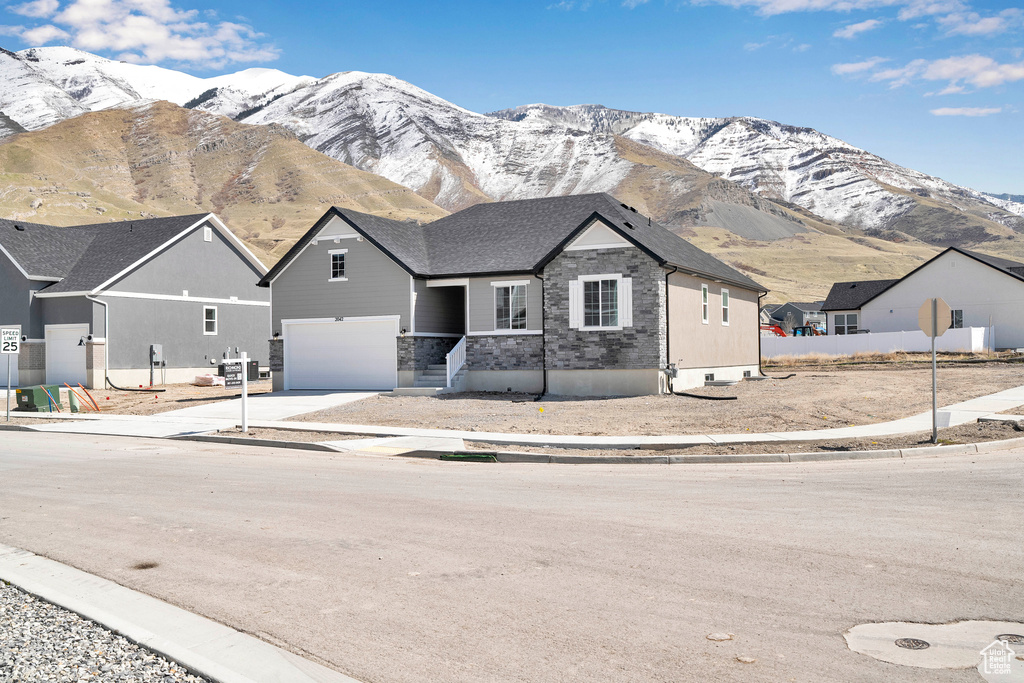 View of front of property with a mountain view, a garage, and concrete driveway