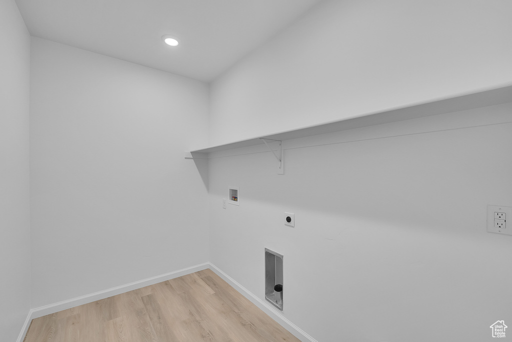 Clothes washing area with laundry area, baseboards, hookup for a washing machine, and light wood-type flooring
