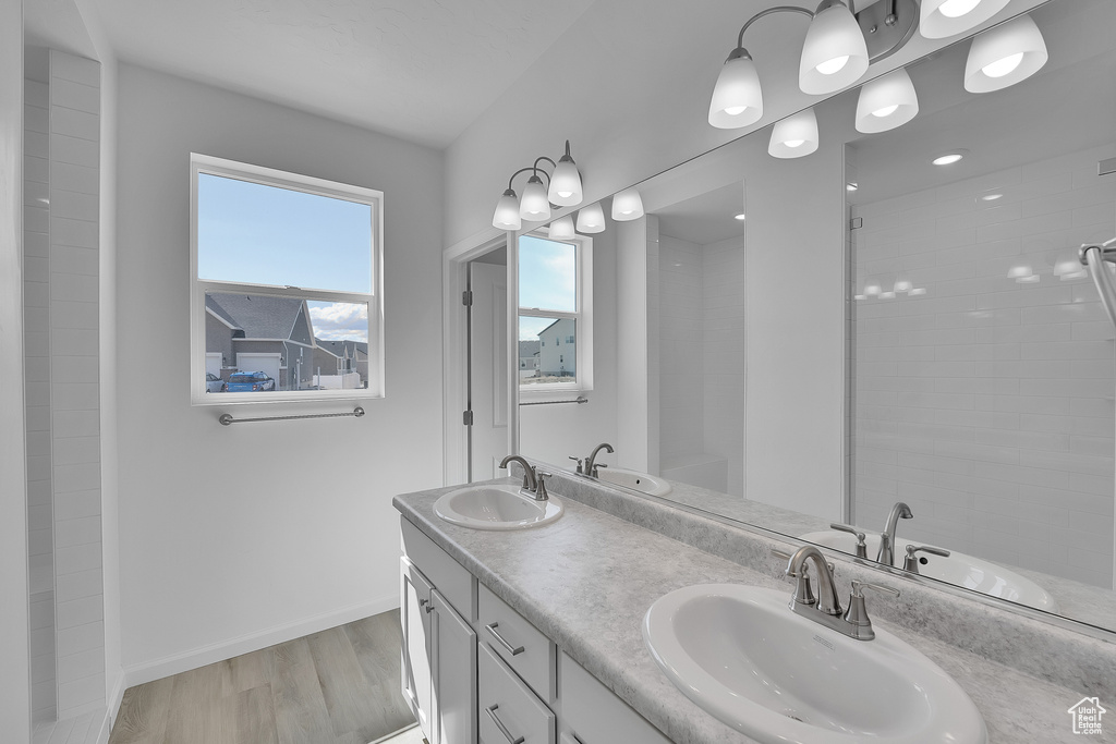 Bathroom featuring a sink, baseboards, double vanity, and wood finished floors