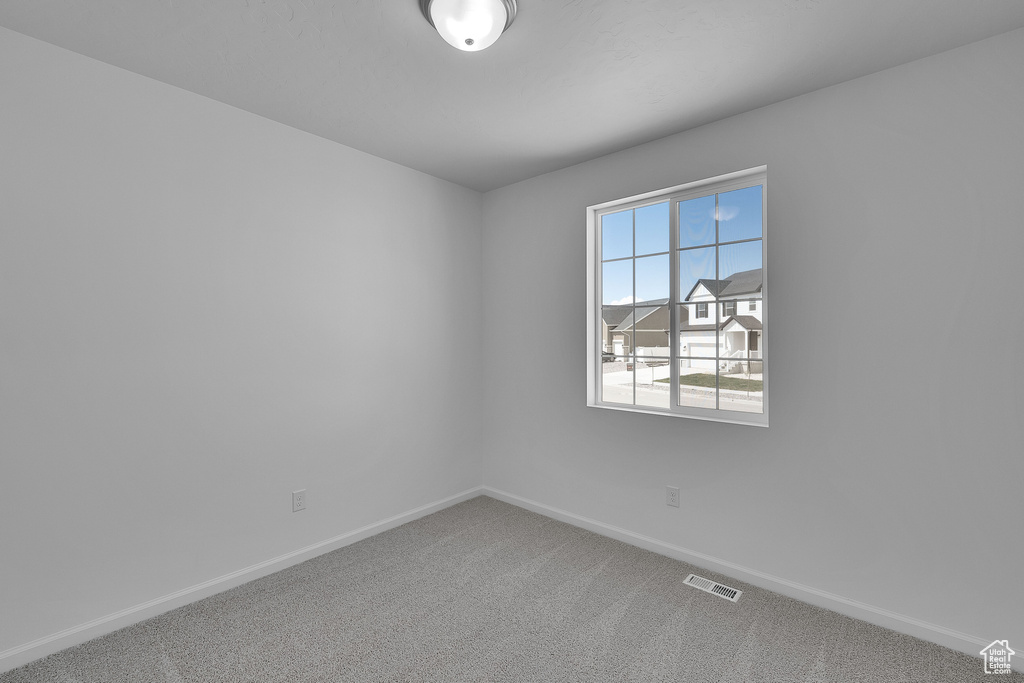 Unfurnished room with carpet, visible vents, and baseboards
