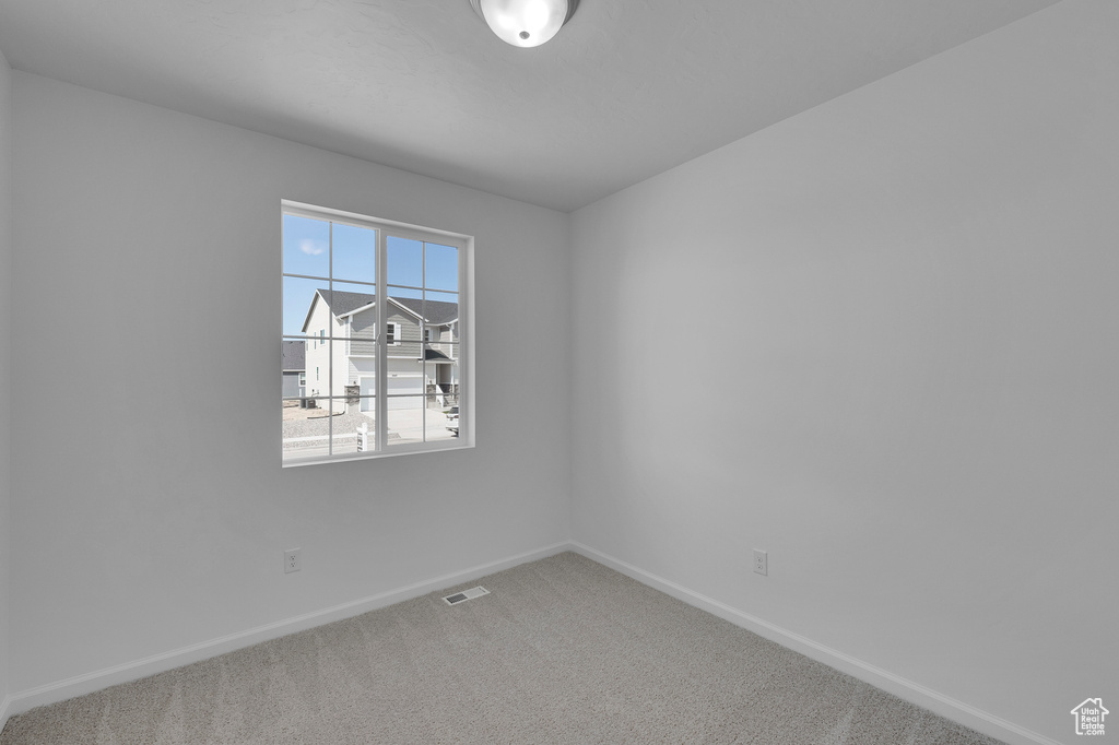 Carpeted empty room featuring visible vents and baseboards