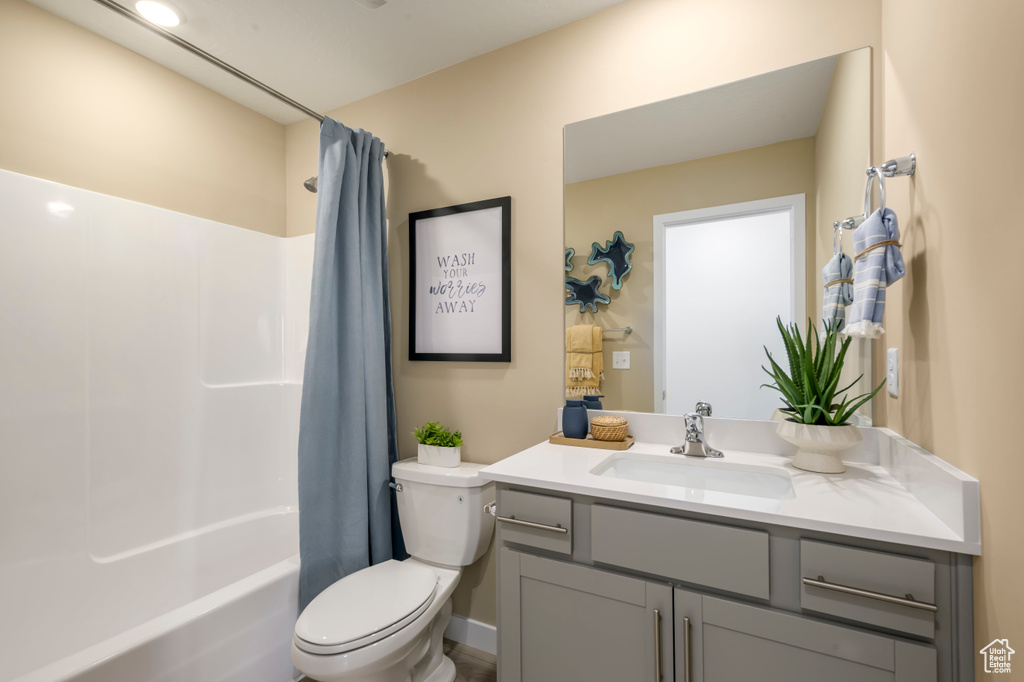 Bathroom featuring shower / bath combination with curtain, vanity, and toilet