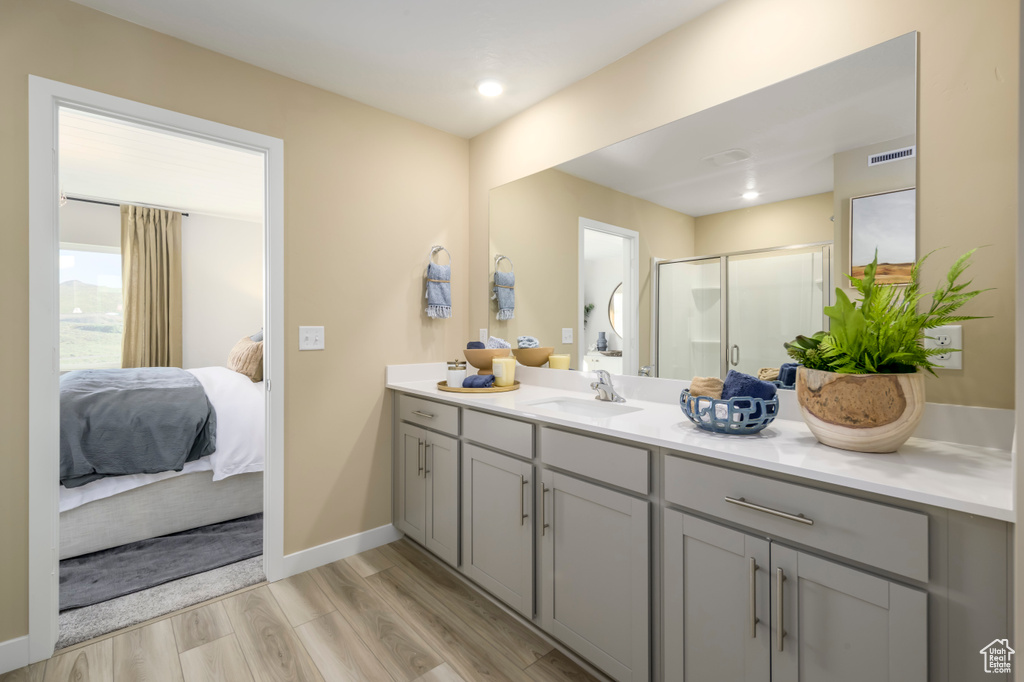 Ensuite bathroom featuring baseboards, ensuite bath, wood finished floors, vanity, and a shower stall