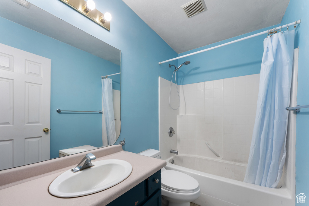 Full bath featuring toilet, shower / bath combo, vanity, and visible vents