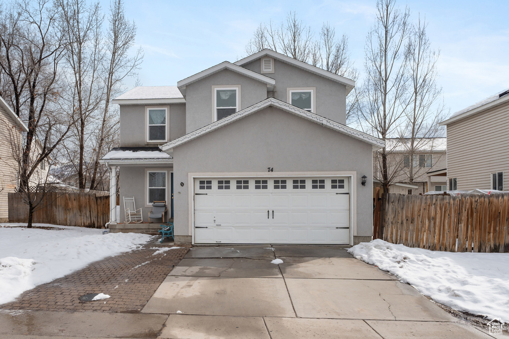 Traditional home with a garage, fence, concrete driveway, and stucco siding