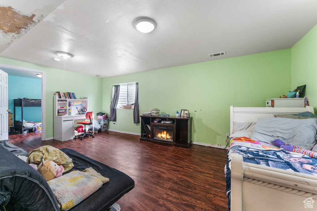 Bedroom featuring visible vents, a fireplace, baseboards, and wood finished floors