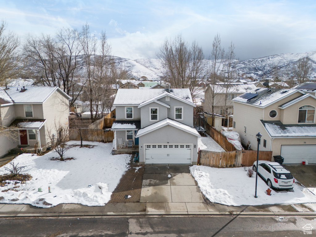 Traditional home with driveway, an attached garage, fence, and a residential view