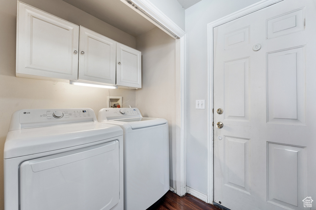 Laundry area featuring separate washer and dryer, dark wood finished floors, and cabinet space