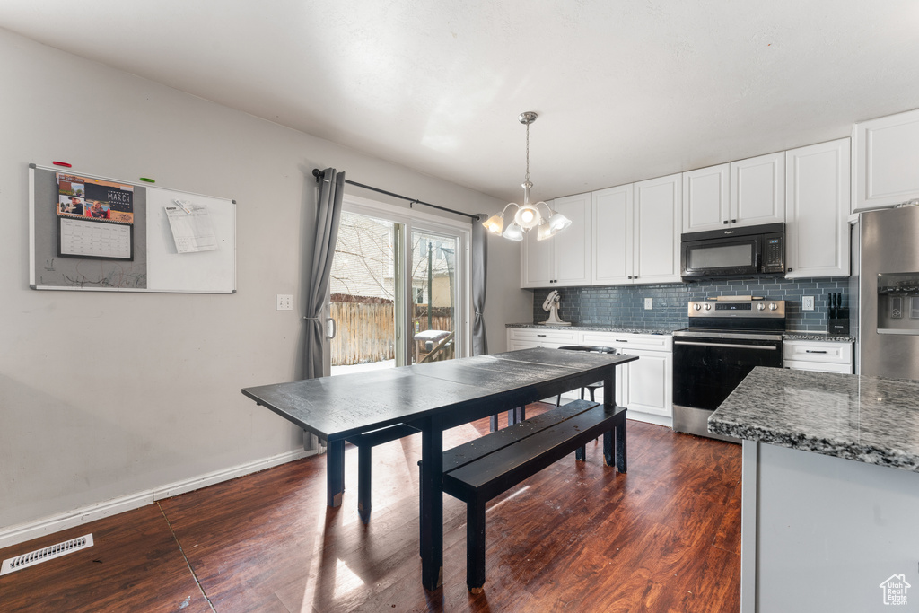 Kitchen with black microwave, range with electric stovetop, white cabinetry, visible vents, and decorative backsplash