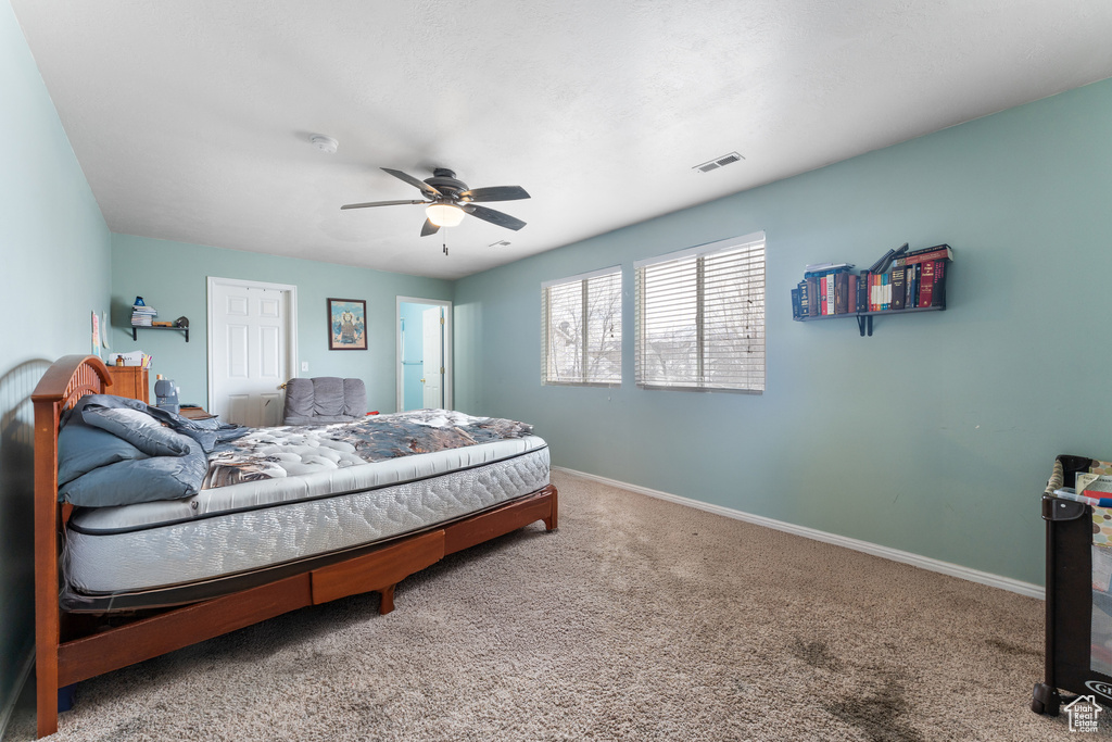 Carpeted bedroom featuring baseboards, visible vents, and ceiling fan