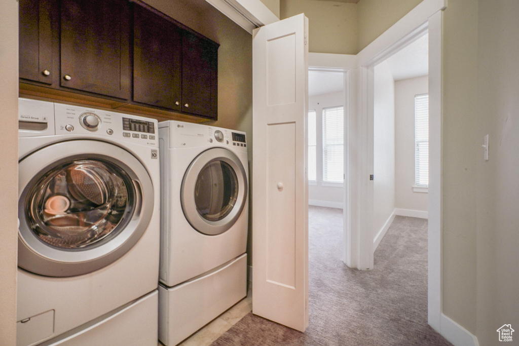 Laundry room with cabinet space, independent washer and dryer, and light colored carpet