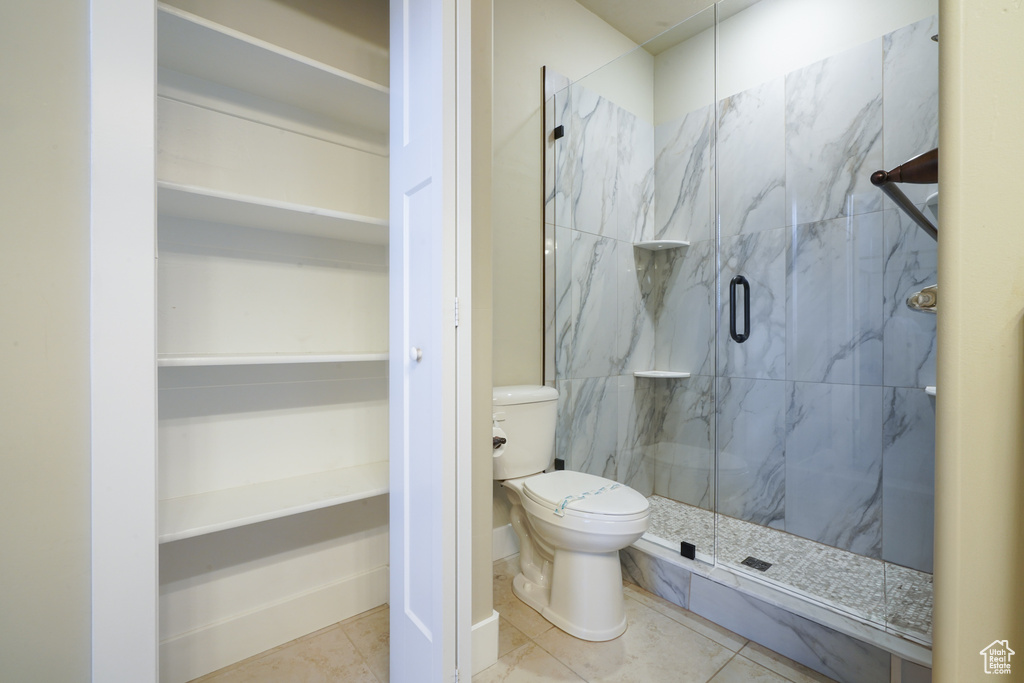 Bathroom featuring a marble finish shower, tile patterned floors, and a walk in closet