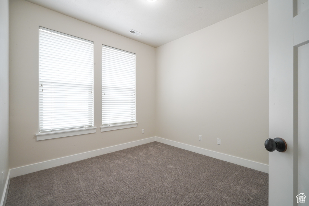 Empty room with dark colored carpet and baseboards
