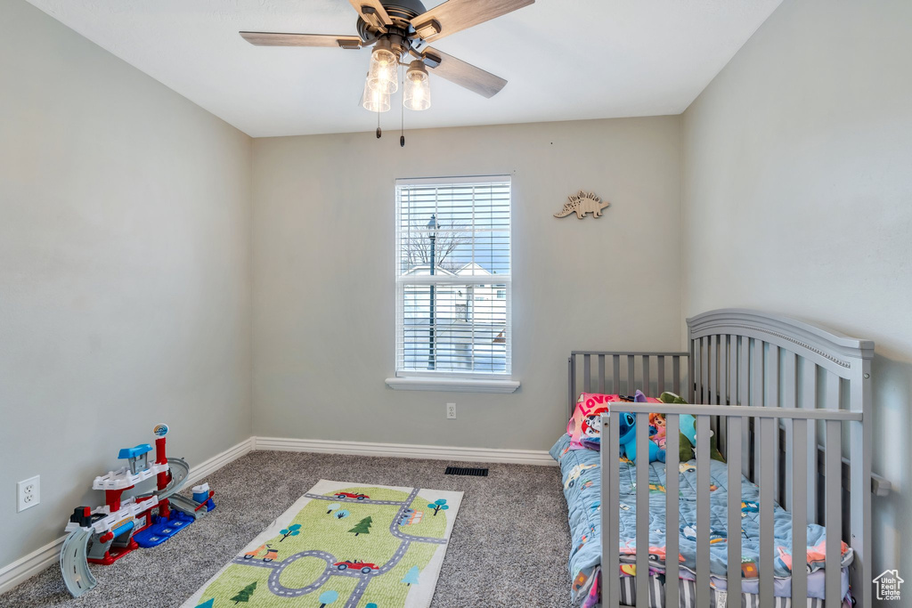 Bedroom featuring carpet floors, visible vents, a crib, and baseboards
