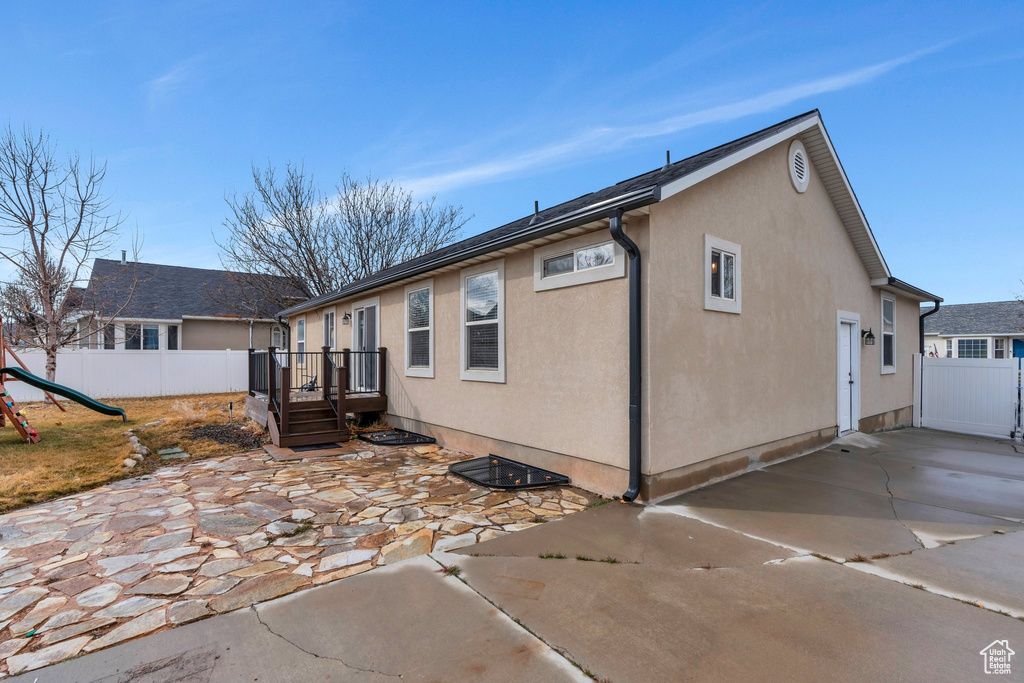 Back of property with a playground, a patio area, fence, and stucco siding