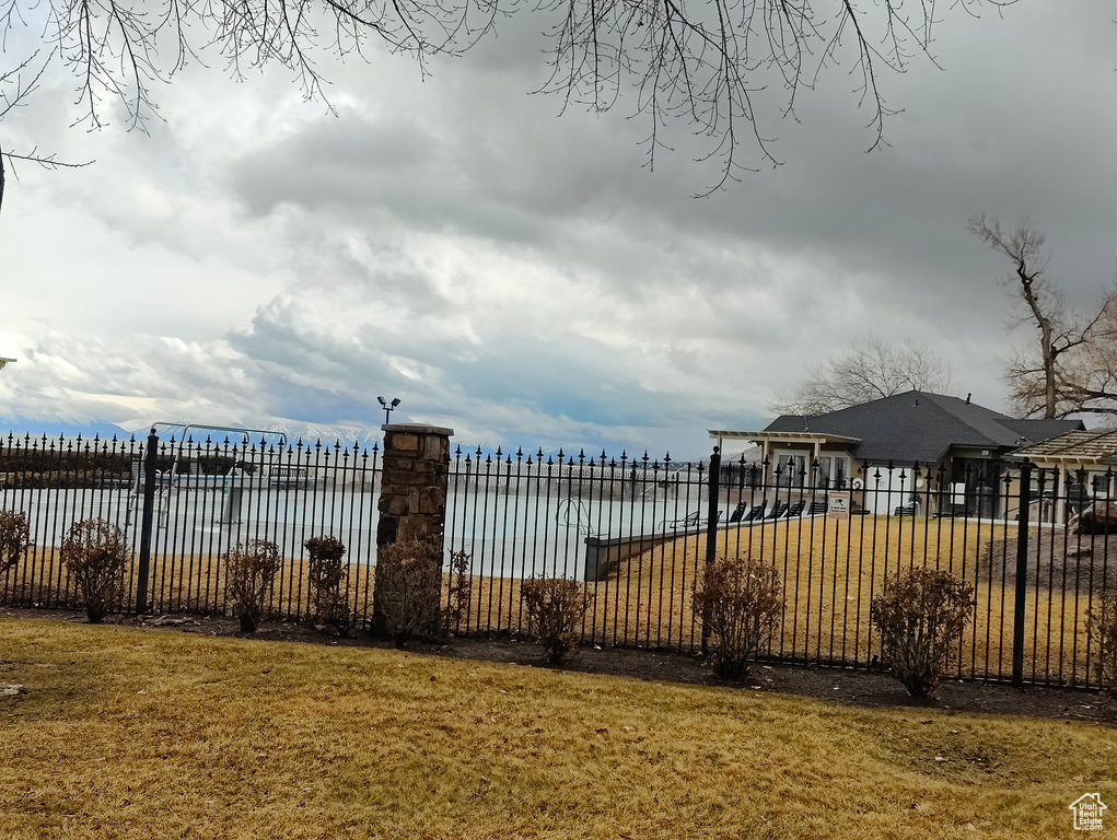 View of gate featuring a water view, fence, and a lawn