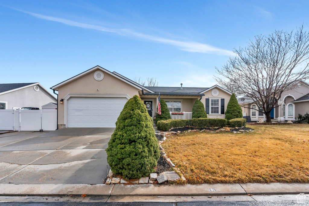 Ranch-style house with concrete driveway, stucco siding, an attached garage, fence, and a front yard