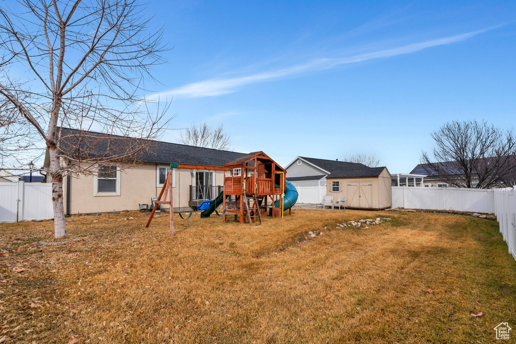 Rear view of property with a lawn, a fenced backyard, an outbuilding, a shed, and stucco siding