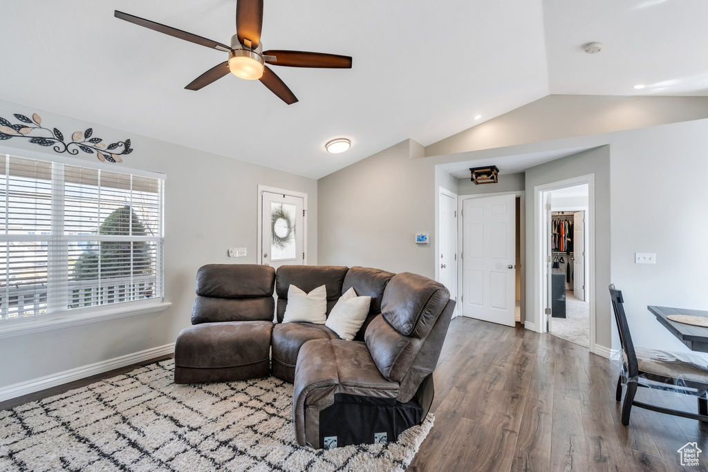 Living area featuring ceiling fan, baseboards, vaulted ceiling, and wood finished floors