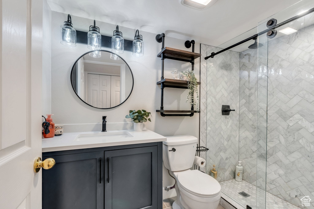 Full bath with toilet, a stall shower, and vanity