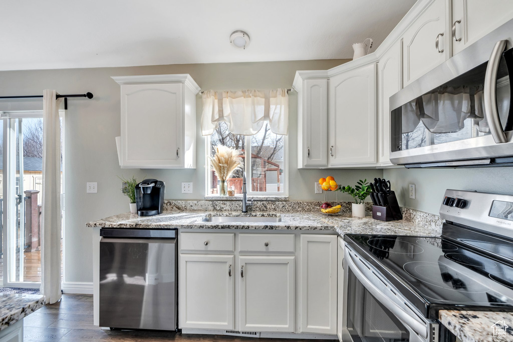 Kitchen featuring stainless steel appliances, a wealth of natural light, white cabinetry, and a sink