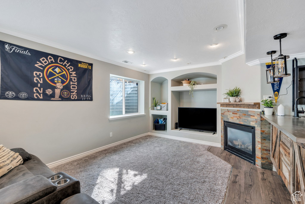 Living room featuring built in shelves, a fireplace, wood finished floors, visible vents, and baseboards