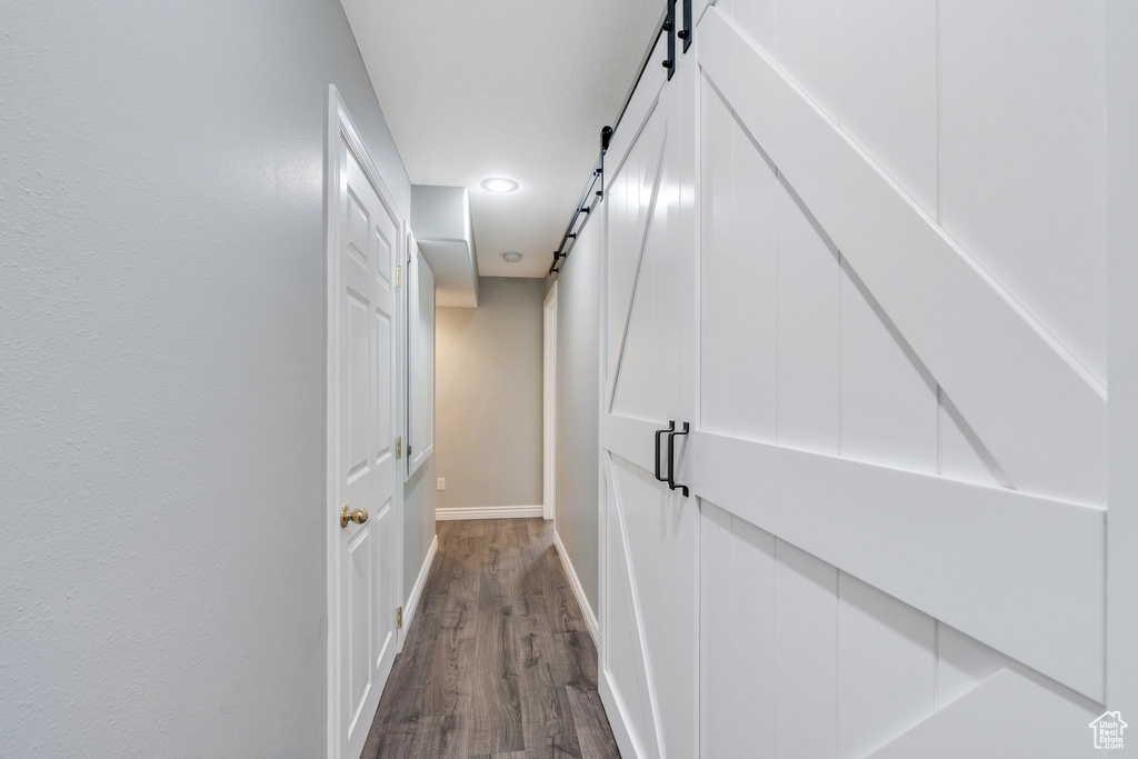 Hallway with a barn door, baseboards, and dark wood finished floors